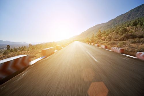 Truck point of view driving on a mountain highway into the morning sun